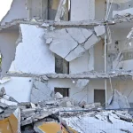 Concrete building dismantled, revealing interior floors with debris and structural damage
