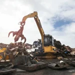 Heavy equipment with hydraulic grapple sorting metal and construction waste at demolition site