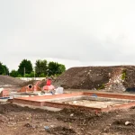 Construction site with excavator and building foundation.