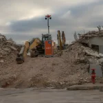 Construction site with excavators and demolition debris piles, showing post-demolition cleanup operations