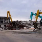 Three excavators working together on commercial building demolition and material sorting