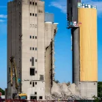 Partial demolition of waterfront grain silos with heavy equipment and debris management
