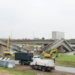 Excavators dismantling concrete bridge sections with debris removal trucks