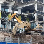 Heavy machinery systematically demolishing multi-story commercial building site
