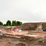 Heavy equipment debris removal, site grading, and foundation preparation in progress