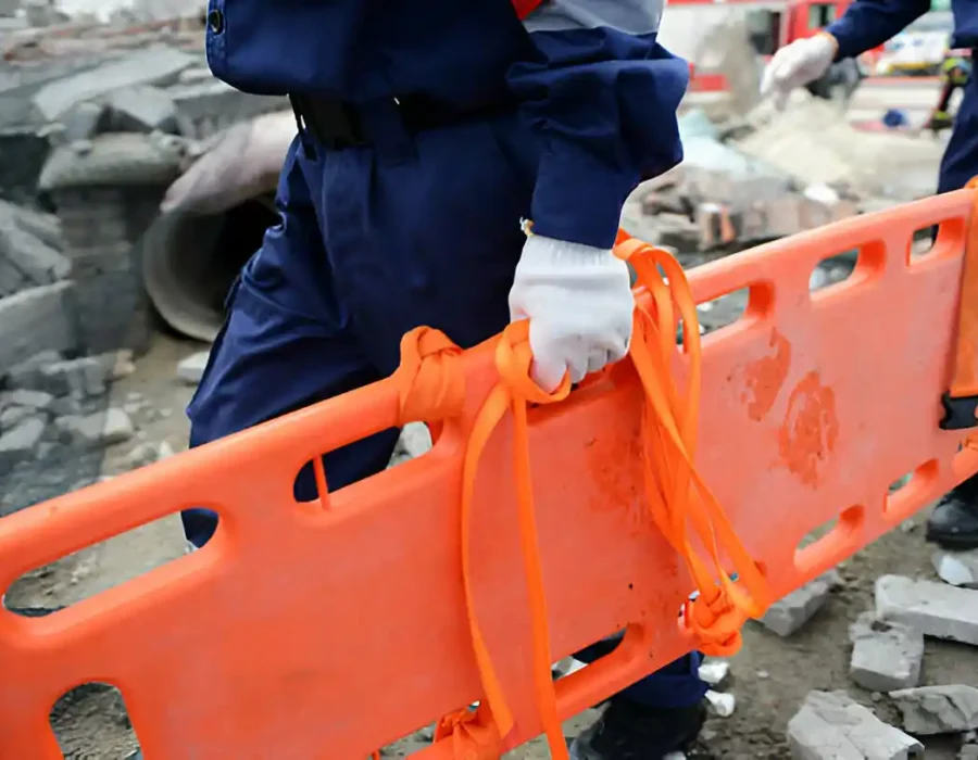 Rescue team transports a stretcher amid debris at a demolition site for safety and cleanup.
