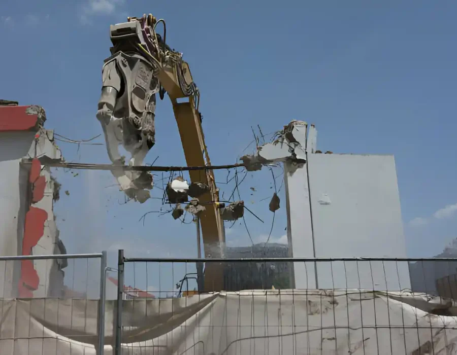 Excavator tearing down a building, creating debris for cleanup and site preparation