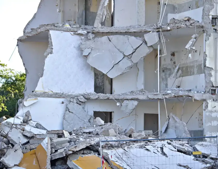 Cracked white building layers, massive concrete debris, progressive demolition site