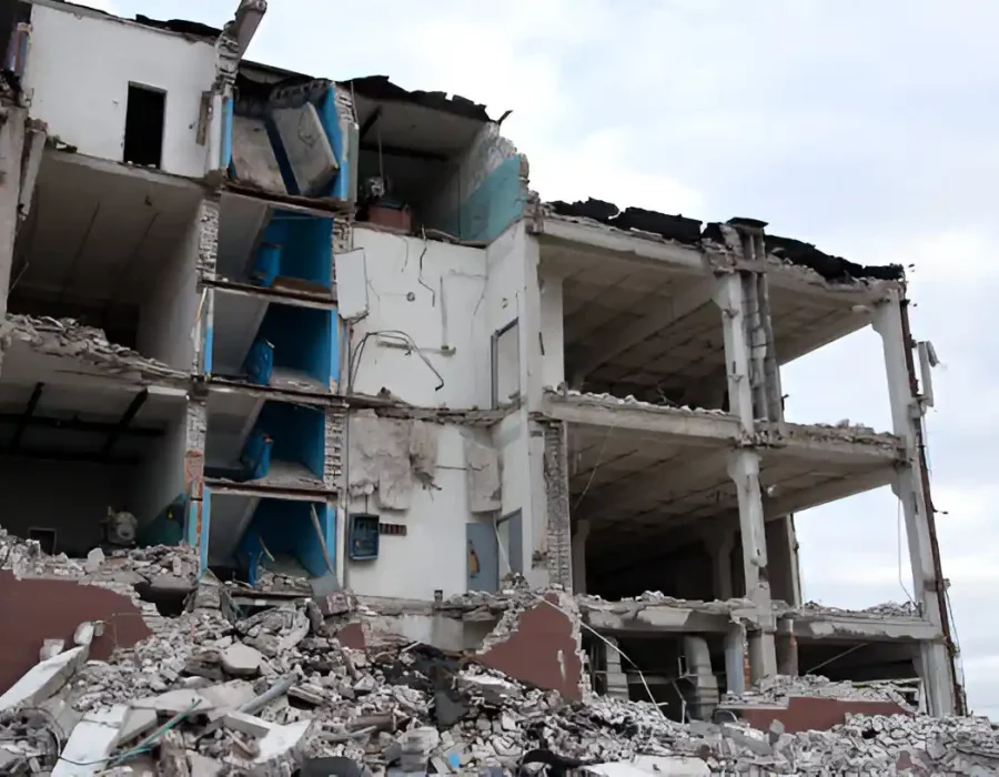 Partially demolished white building, exposed blue interior, concrete debris, progressive deconstruction