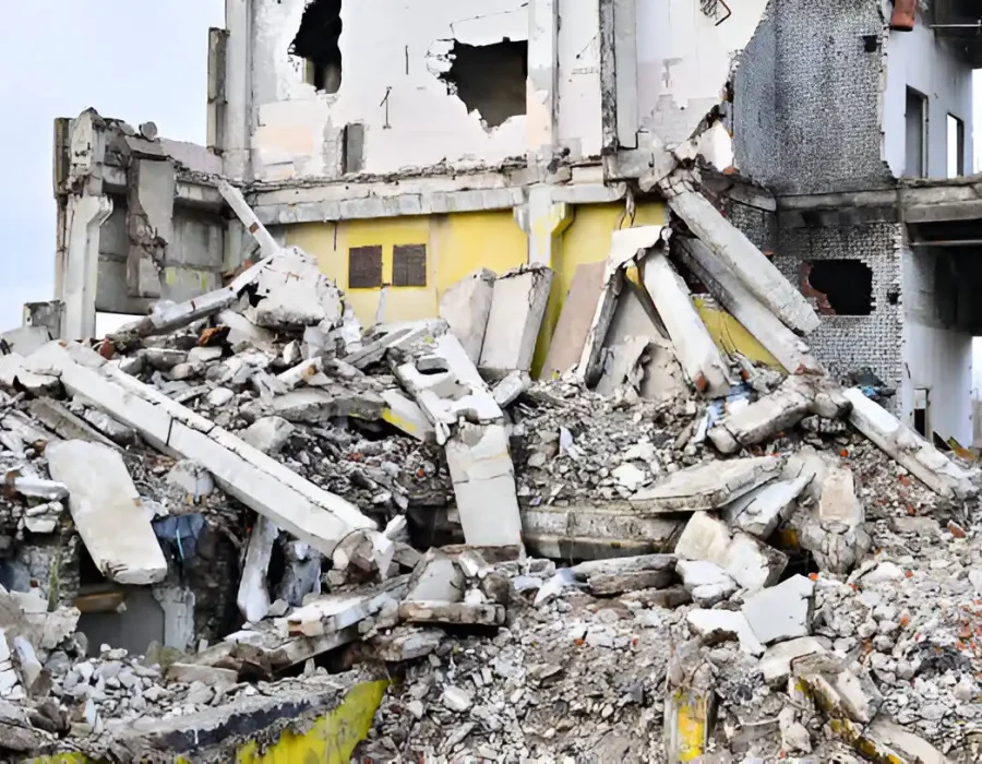 Collapsed concrete building with massive debris, yellow walls, extensive structural damage