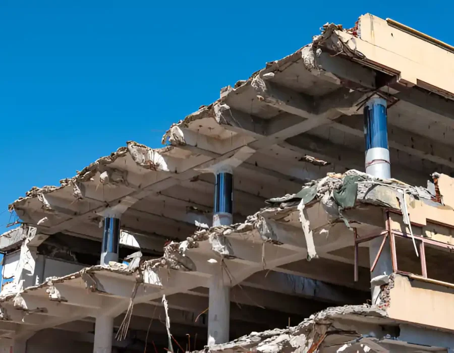 Partially demolished multi-story concrete building with exposed floors and blue sky