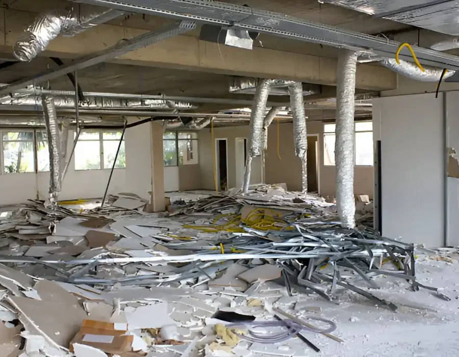 Gutted office interior with scattered debris, exposed HVAC and structural elements