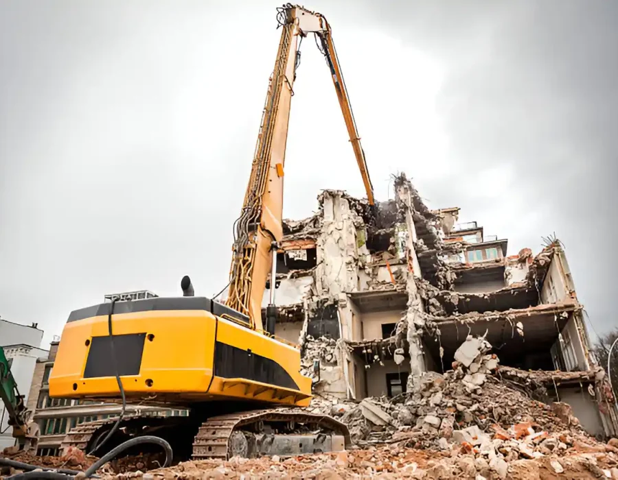 Yellow long-reach excavator dismantling concrete building with precise destruction