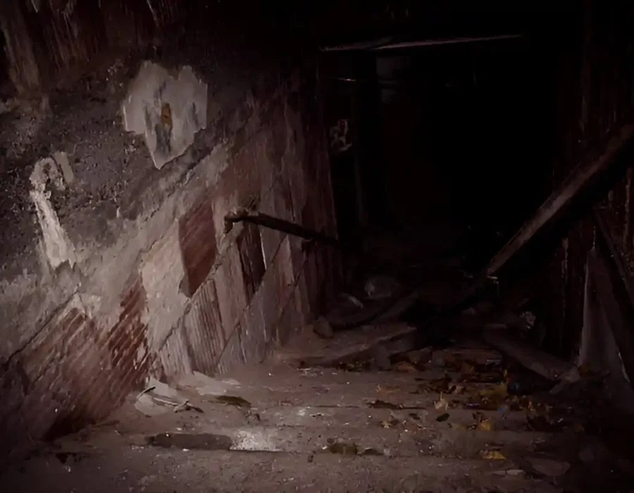 Dark basement with damaged walls and scattered debris.