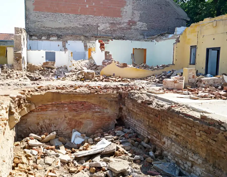Demolished building with rubble and exposed foundation walls.