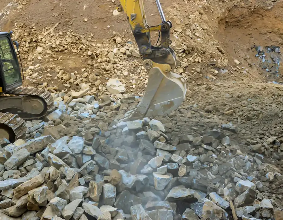 Excavator breaking rocks during site preparation and debris removal.
