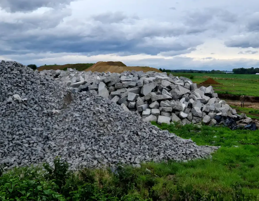 Piles of rubble and debris at a construction site under cloudy skies.