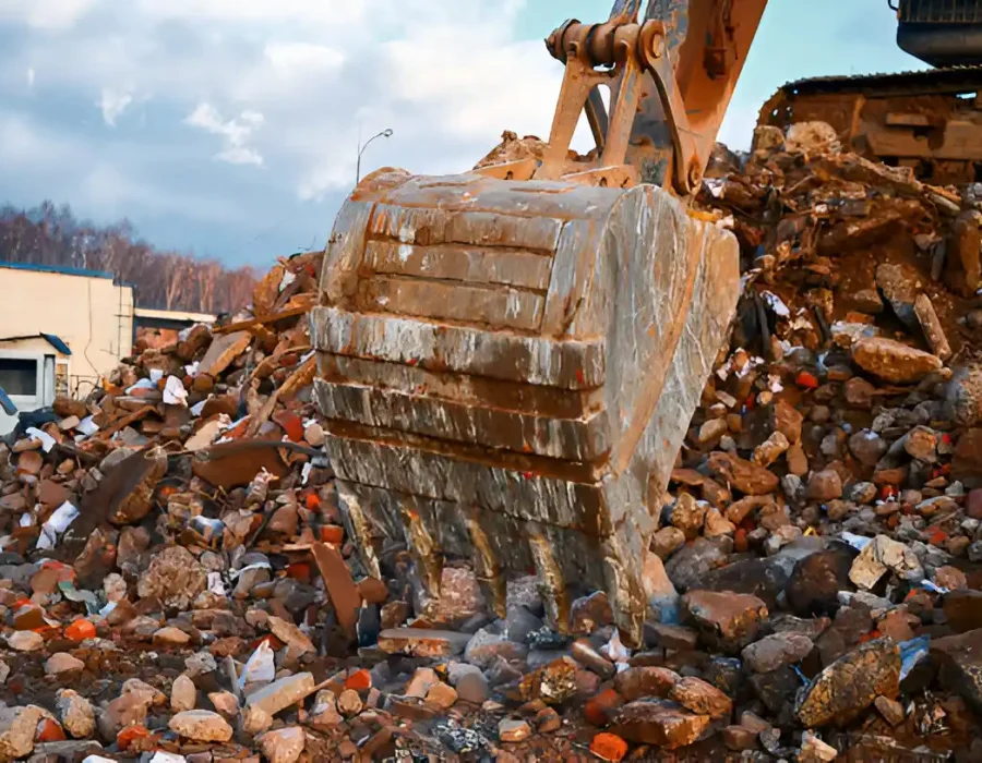 Excavator bucket removing rubble from a demolition site.