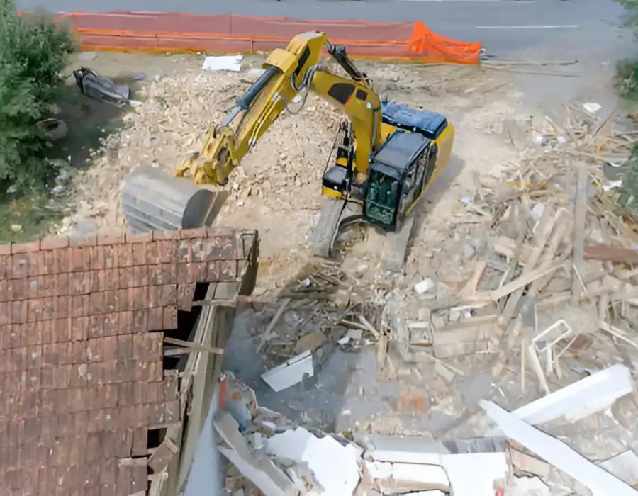 Aerial view of excavator removing roof structure and sorting mixed demolition materials