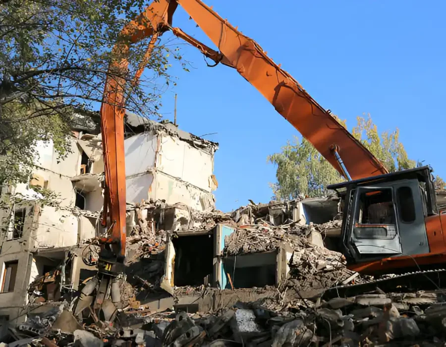 Long-reach excavator demolishing multi-story apartment building with precision control