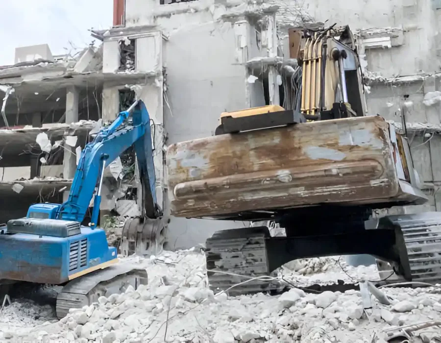 Multiple excavators working on commercial demolition site with concrete debris removal