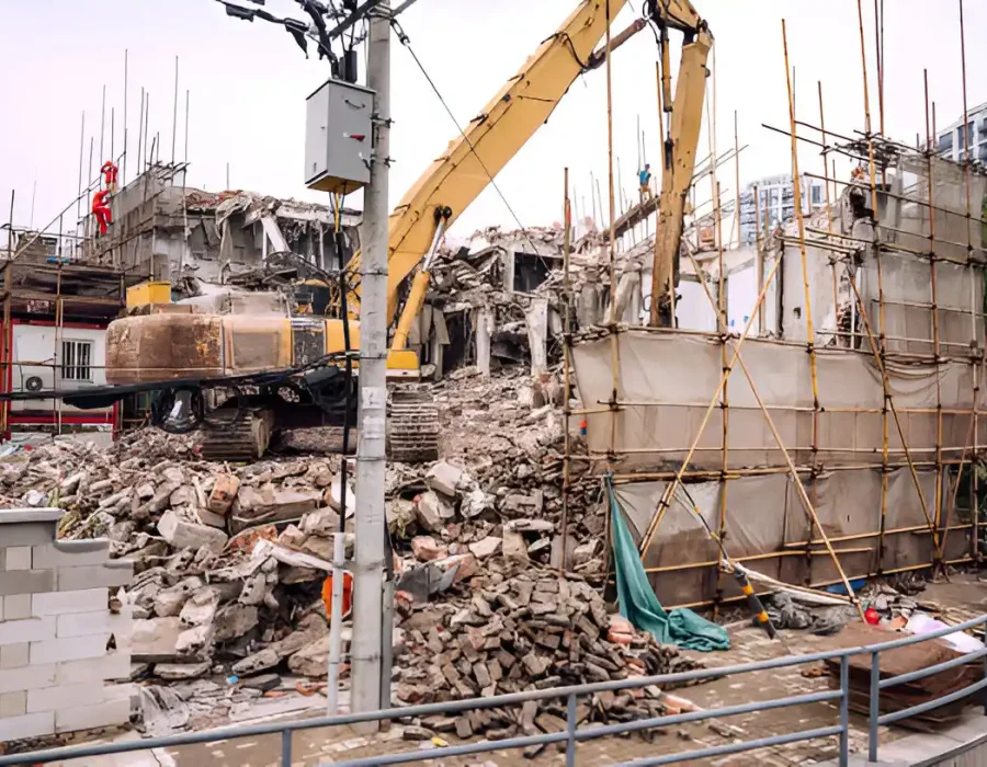 Excavator demolishing building with scaffolding and safety barriers in downtown setting