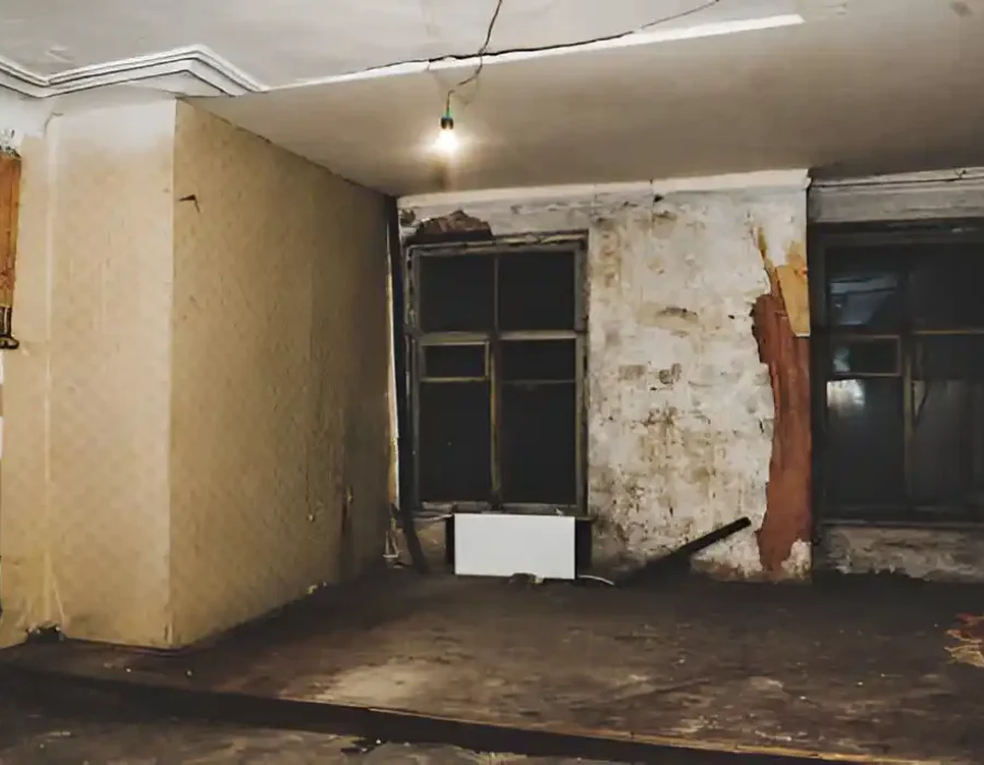 Old room interior with peeling walls and damaged flooring for demolition service.