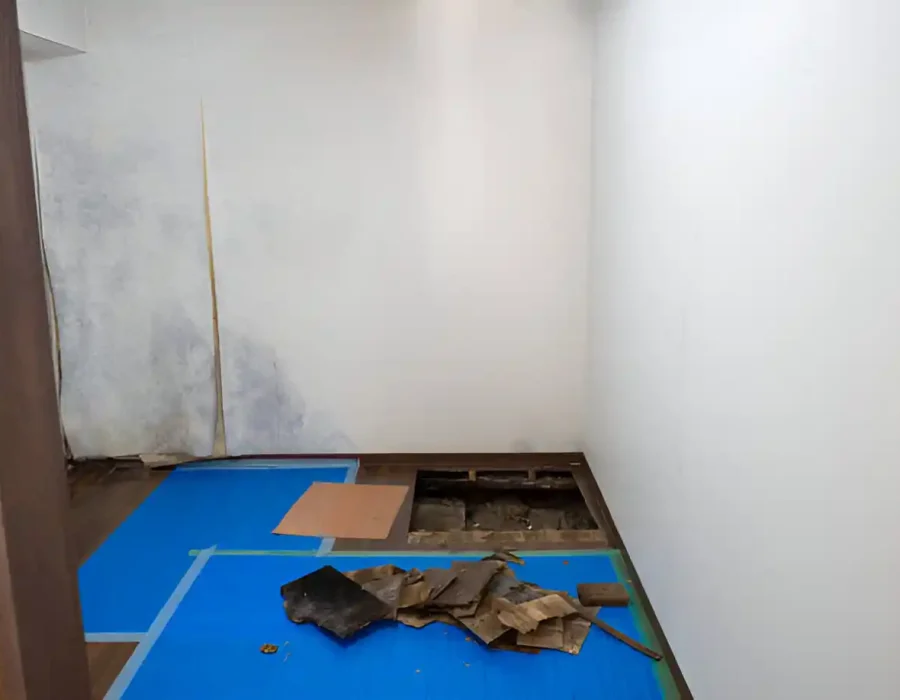 Partially demolished room with debris and blue tarp on the floor.