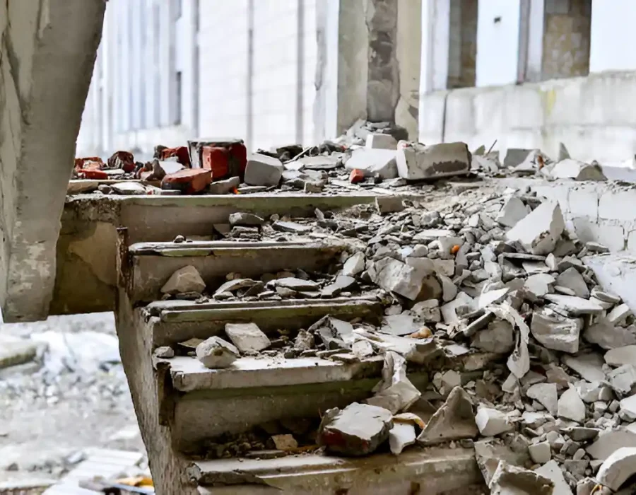 Demolished concrete staircase covered in construction rubble during interior renovation project