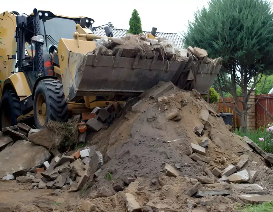 Heavy equipment removing soil and construction debris during residential demolition cleanup