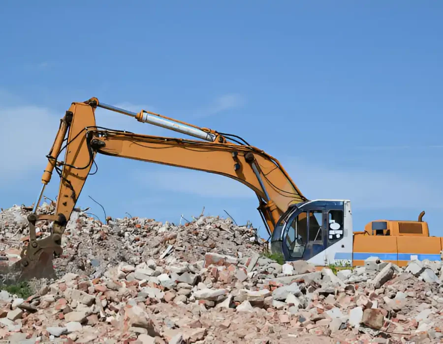 Large excavator sorting concrete rubble and brick debris at commercial demolition site