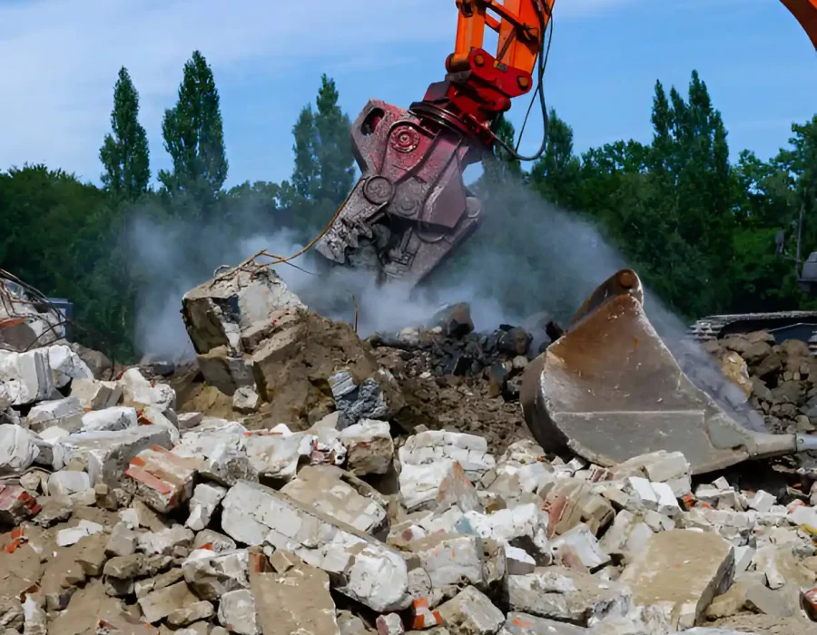 Heavy-duty demolition crusher attachment pulverizing concrete debris with dust control system
