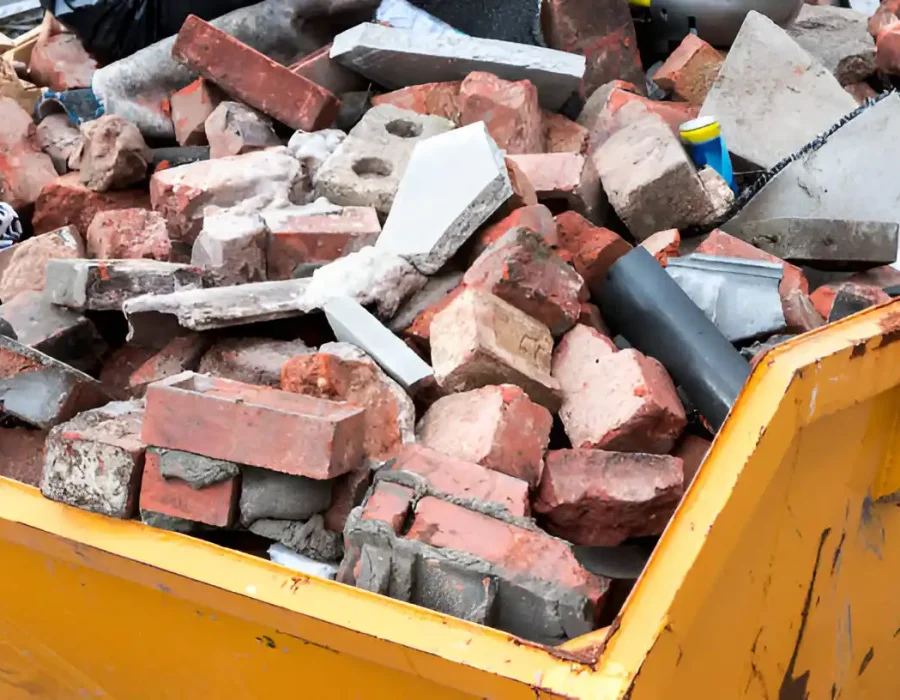 Yellow dumpster filled with broken red bricks and concrete from demolition site cleanup
