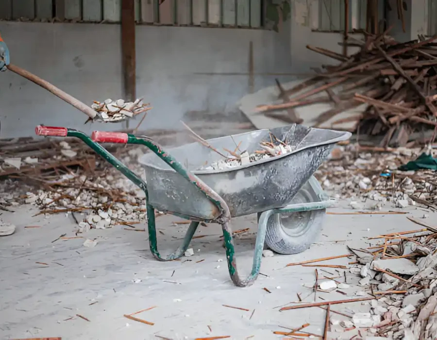 Worker loading construction debris into wheelbarrow during interior demolition cleanup