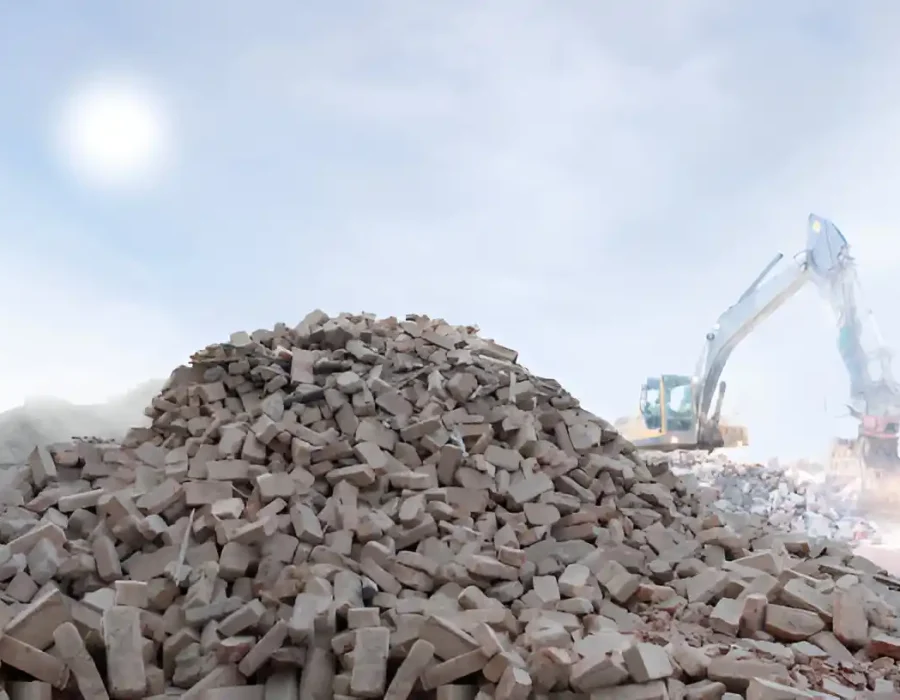 Heavy machinery sorting large pile of concrete rubble at commercial demolition waste facility