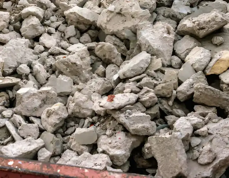 Mobile concrete crusher processing demolition debris with sorted rubble piles and container