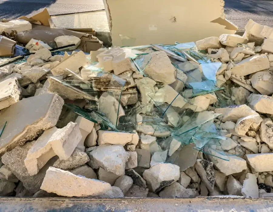 Close-up of construction waste container filled with broken glass, drywall, and concrete debris