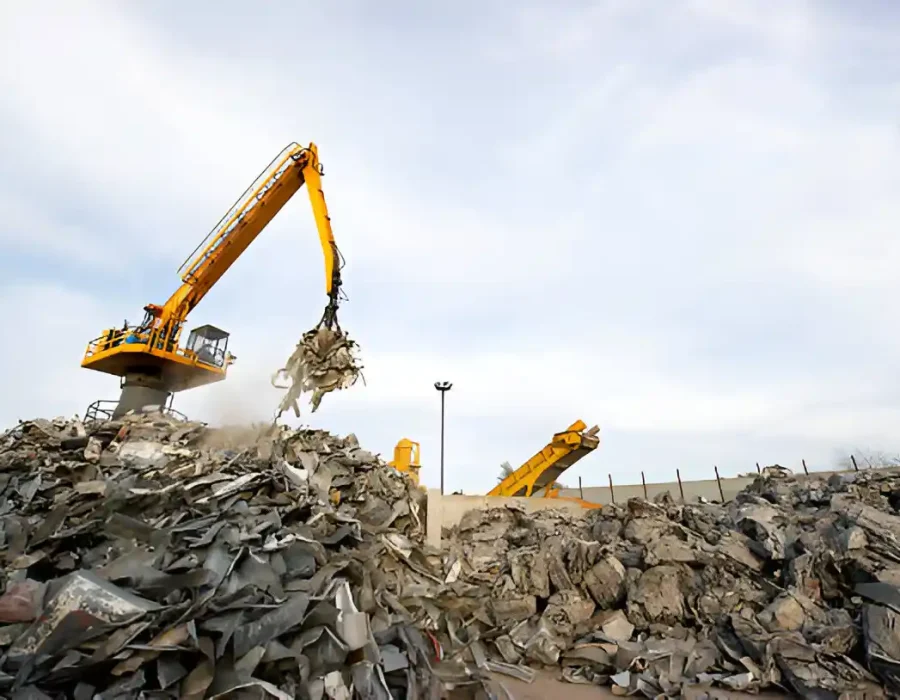 Long-arm excavator sorting demolition waste at industrial recycling site with debris piles