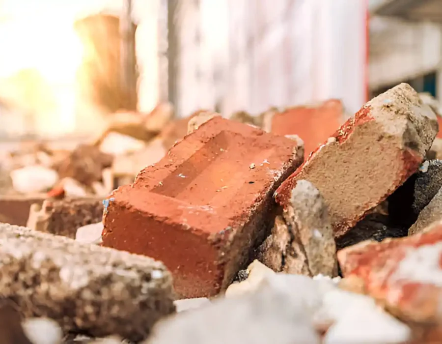 Close-up of broken red bricks and concrete rubble from building demolition site at sunset