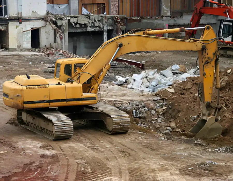 Yellow excavator clearing rubble at urban demolition site