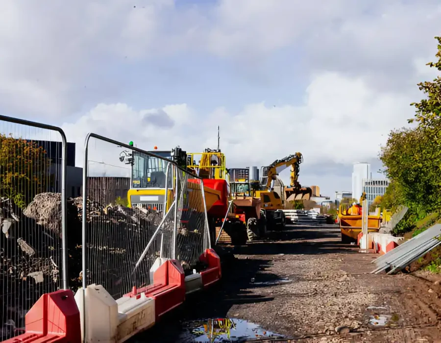 Heavy machinery and barriers at construction site, debris present