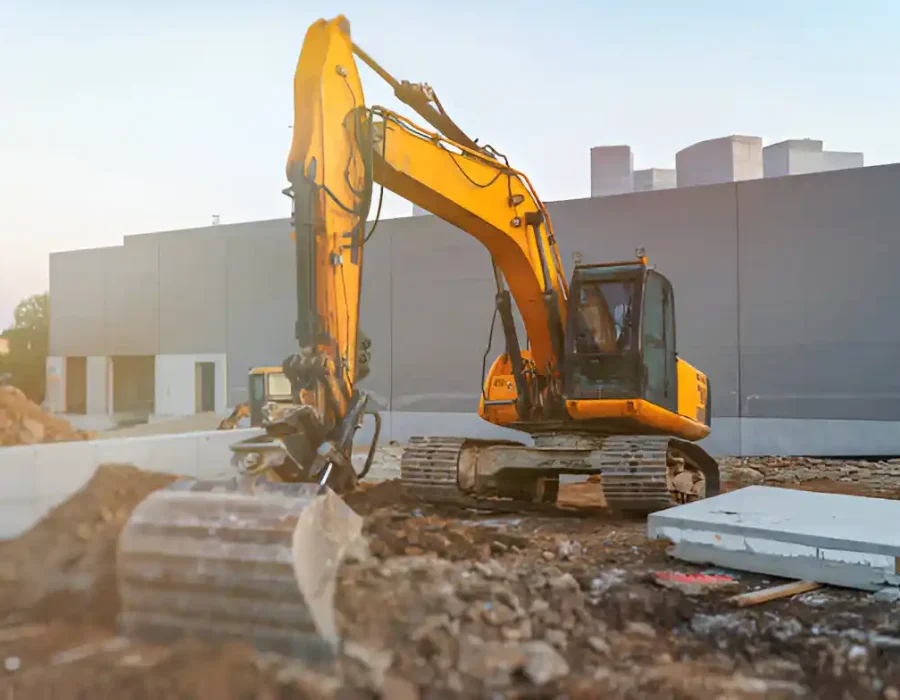 Yellow excavator preparing construction site, clearing debris