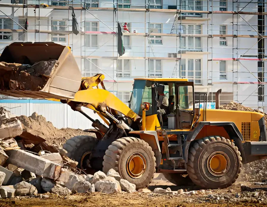 Yellow front loader clearing rubble at construction site