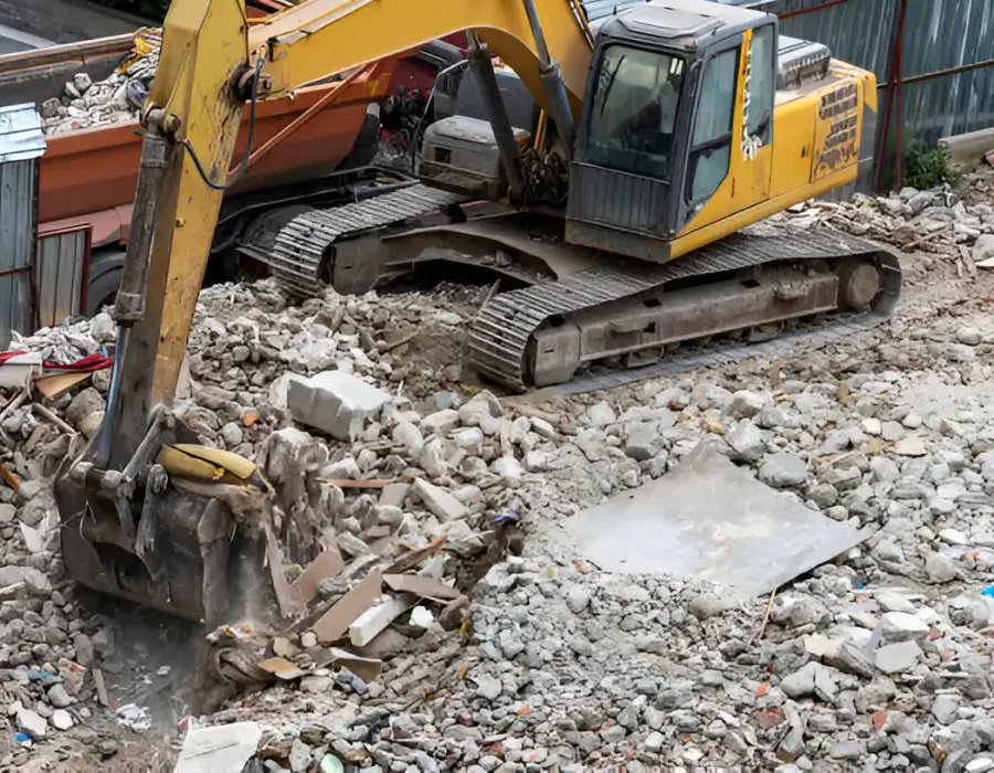 Excavator clearing debris at construction demolition site