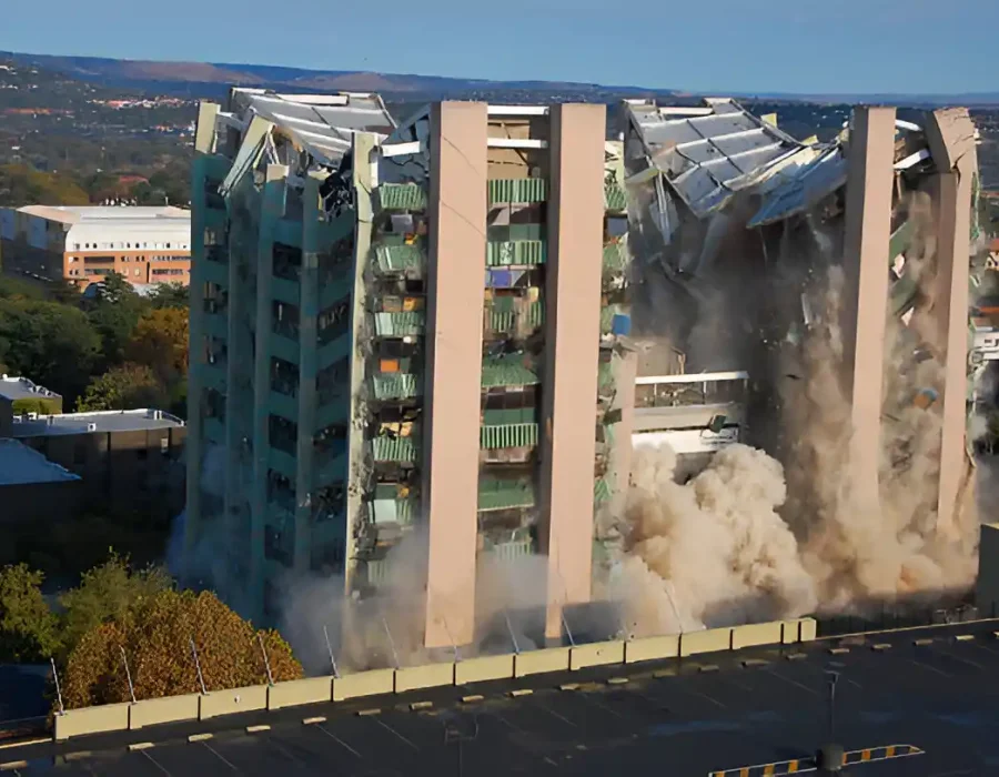 High-rise building collapsing with debris and dust, showcasing demolition and debris removal services.