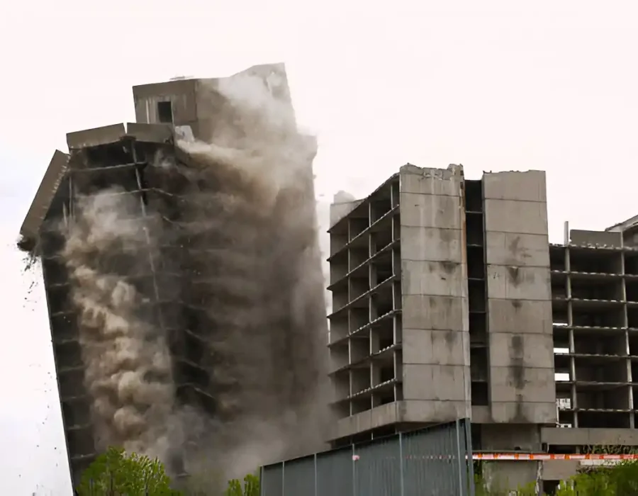 Building collapse in progress with dust cloud, highlighting demolition and debris removal services.
