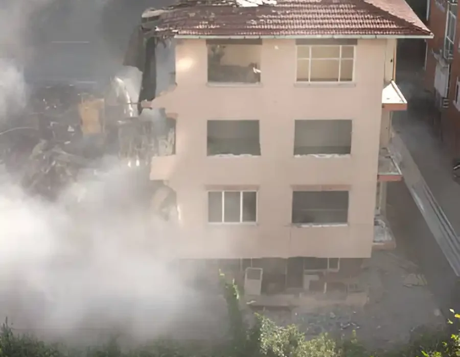 Compact residential building demolition with dust cloud, urban site clearance in progress