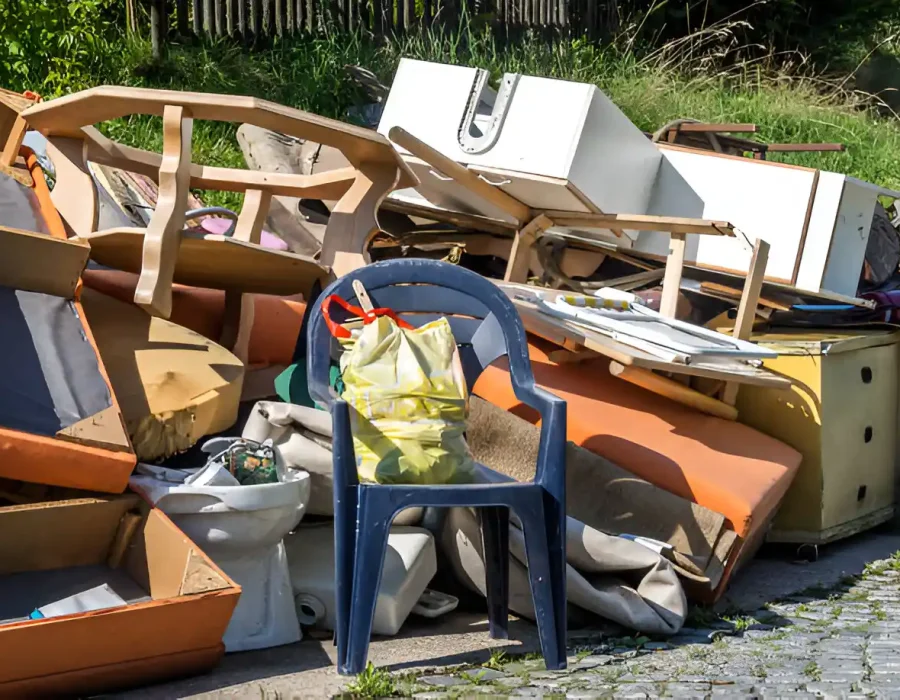 Discarded furniture and household waste pile including chairs and appliances awaiting professional removal service