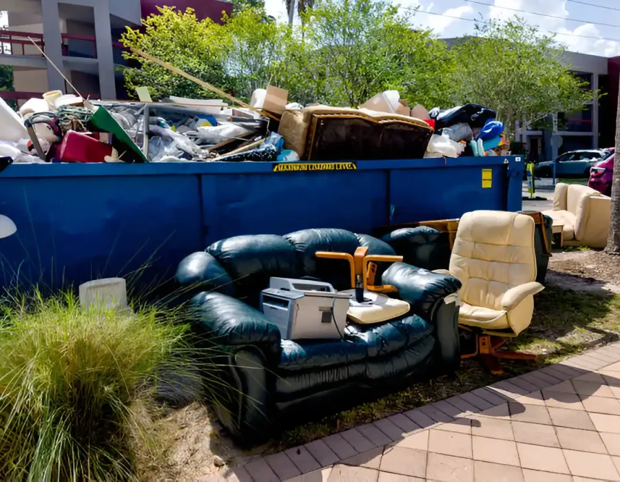 Couch and chairs beside a dumpster filled with debris for efficient cleanup and demolition services