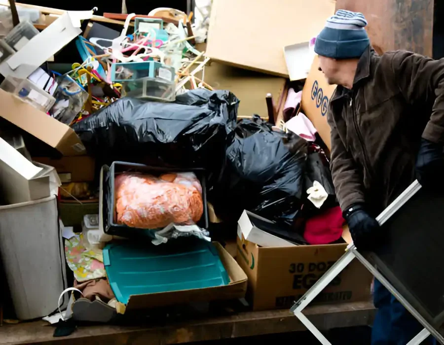 Worker clearing commercial waste and debris during professional cleanup service with boxes and disposal bags